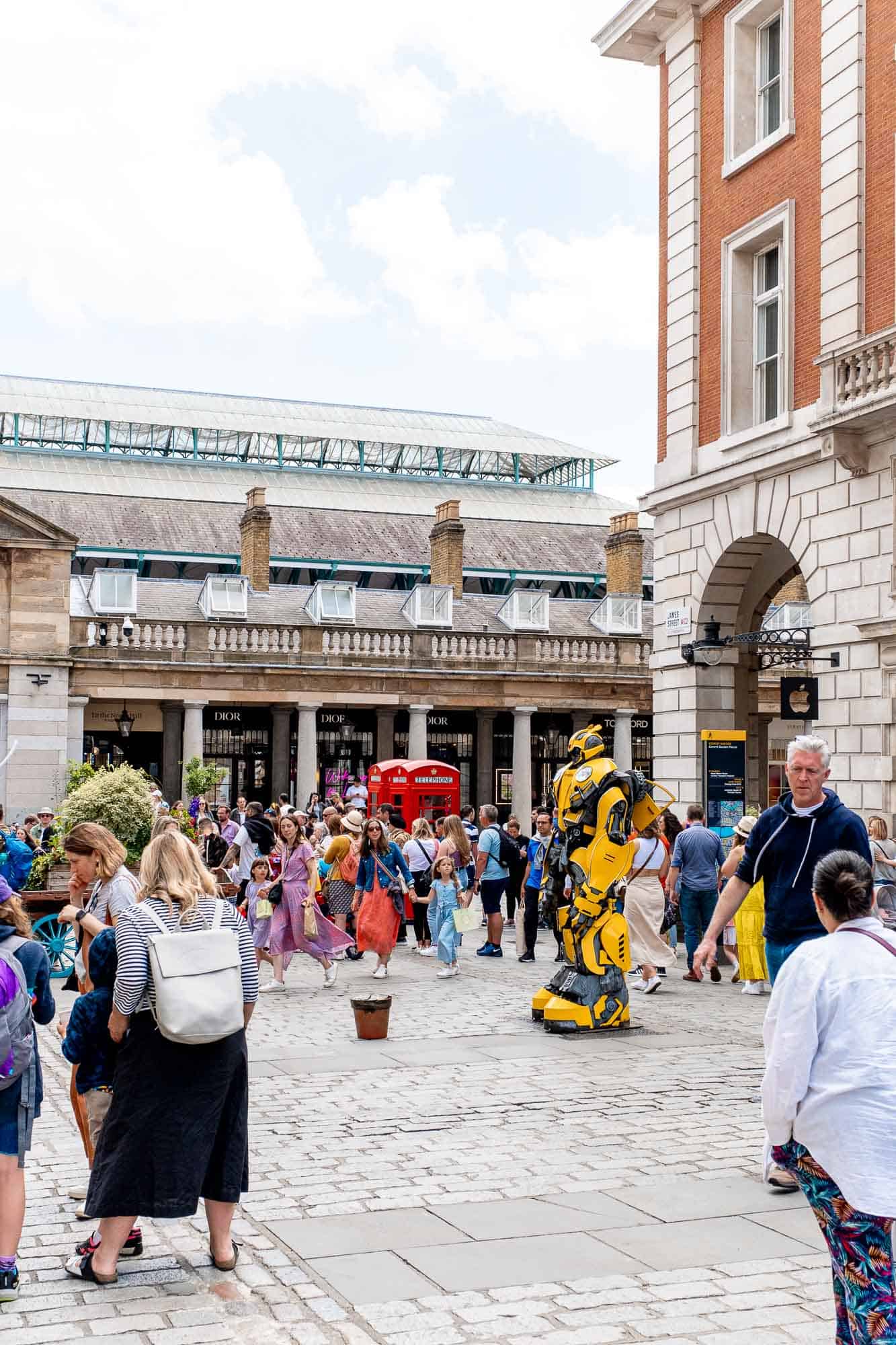 Busy streets of Covent Gardens with street performers dressing Transformers gear