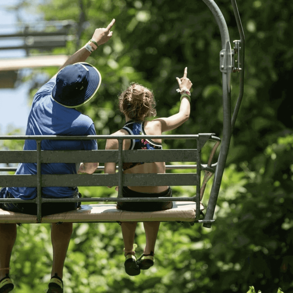 Mystic Mountain Jamaica Rainforest Adventure Review Two people going up the Shy Explorer chair lift at Mystic Mountain Jamaica Rainforest Adventure Review