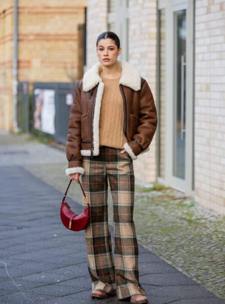 30 Brown Aviator Jacket Plaid Flare Trousers Burgundy Moon Bag retro-inspired winter fashion featuring a brown aviator jacket styled with plaid flare trousers and a burgundy moon bag