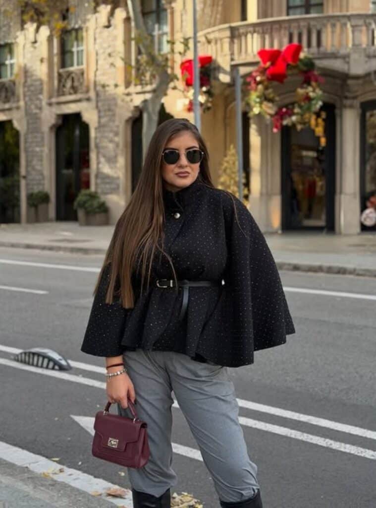 31 Embellished Cape Coat Grey Slim Pants Burgundy Handbag elegant winter travel outfits in spain styled with an embellished cape coat paired with grey slim pants and a burgundy handbag
