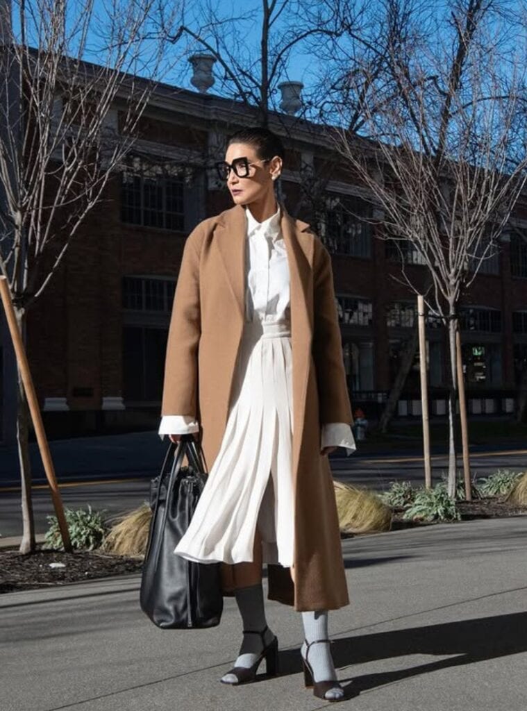9 Camel Maxi Overcoat White Pleated Midi Skirt Black Oversized Tote chic european winter outfits with a camel maxi overcoat paired with a white pleated midi skirt and black oversized tote